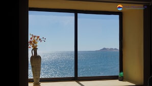 Una habitación con un ventanal grande que da a una masa de agua y una montaña distante.