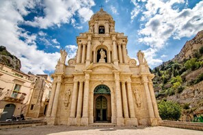 A historic church with a bell tower, arched entrance, and statues.