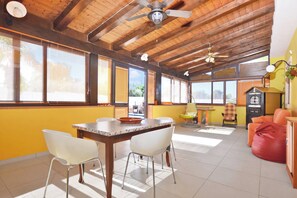 A spacious room with a high ceiling, wooden beams, a dining table with chairs, a sofa, and a vintage radio. - Casa Plaja, Scicli, Italy (Scicli)