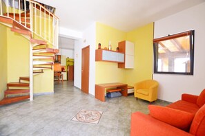 A living room with a staircase, a sofa, a chair, and a desk.
