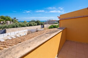 A balcony with a view of the sea, a stone wall, and a row of sun loungers. - Casa Plaja, Scicli, Italy (Scicli)