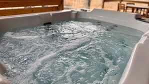 A hot tub with visible bubbles, surrounded by wooden slats and a tiled wall. - Squirrel's Nest (Fort Payne)