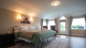 A bedroom with a bed, a nightstand, a wall-mounted lamp, a window with curtains, and a view of the outdoors. - Benchwarmer`s Bliss (Homer)