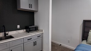 A compact kitchen with grey cabinets, a black microwave, and a sink. - Charming -Cozy private studio Bedroom! (Dallas)