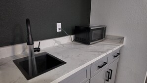 A kitchen with a sink, a microwave, and a black faucet. - Charming -Cozy private studio Bedroom! (Dallas)