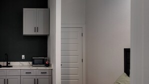 A bedroom with a bed, a nightstand, a microwave, and a cabinet. - Charming -Cozy private studio Bedroom! (Dallas)