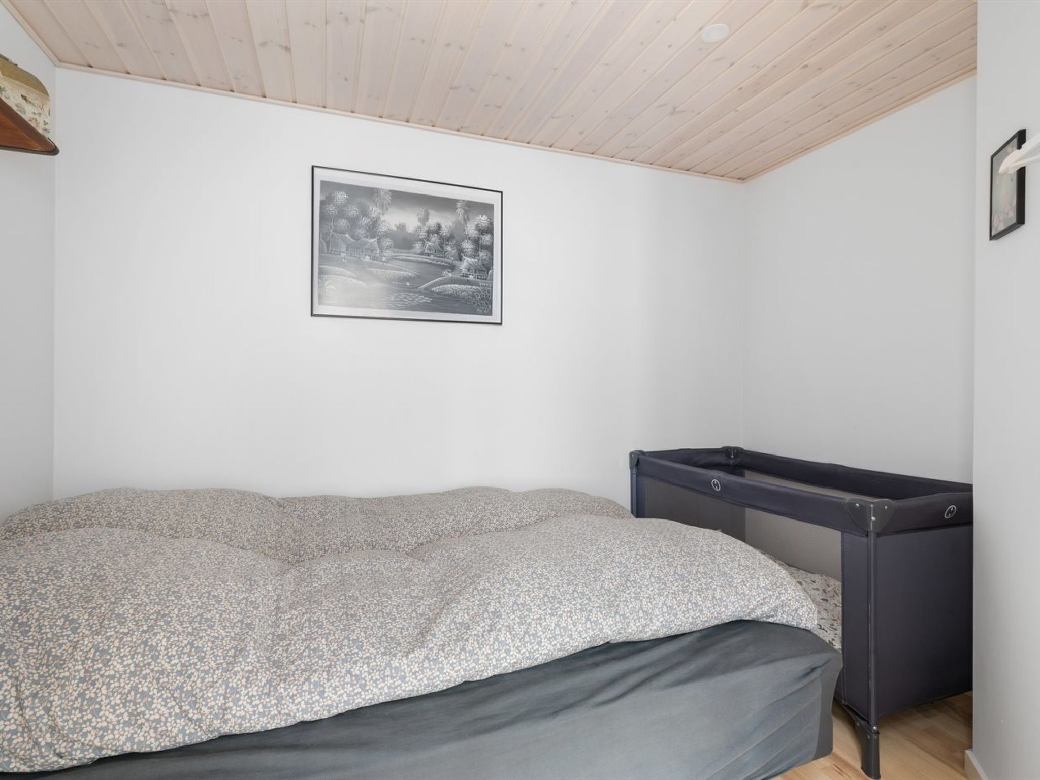 Une chambre à coucher avec un lit, un petit bureau et un tableau encadré accroché au mur.