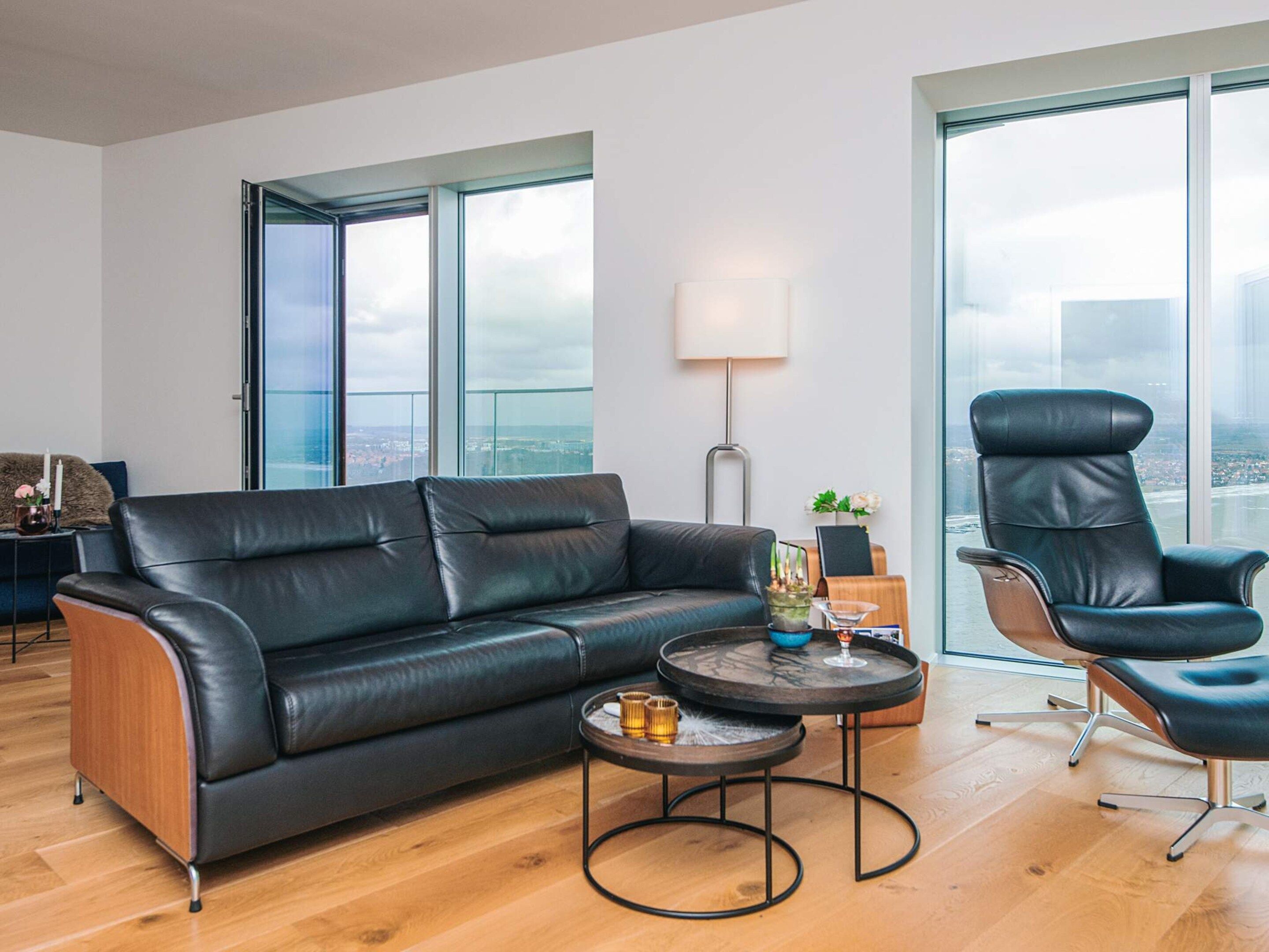 A modern living room with a leather sofa, a round coffee table, and a high-back chair.