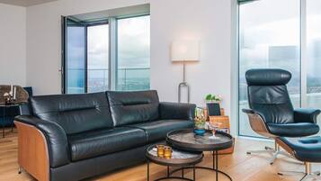 A modern living room with a leather sofa, a round coffee table, and a high-back chair.