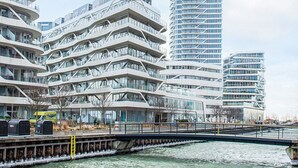 A modern high-rise building with multiple balconies and large windows, situated near a body of water. - 5 Star Holiday Home in Aarhus C (Aarhus)