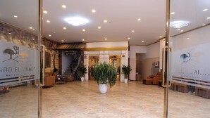 A hotel lobby with a marble floor, potted plants, and a reception desk. - Flamant Boutique Hotel (Sa Pa)