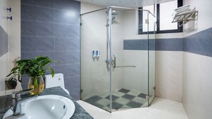 A modern bathroom with a glass shower enclosure, a white sink, and a potted plant. - Flamant Boutique Hotel (Sa Pa)