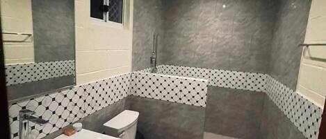 Un baño moderno con ducha, inodoro y lavamanos.