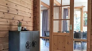 Et interiør af en træhytte med et gråt skab, en dør der fører til et spiseområde, og en lille potteplante på skabet.