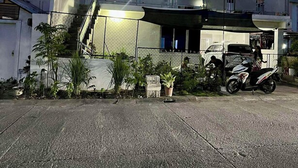 Una casa de dos pisos con un balcón, una escalera y una moto estacionada.