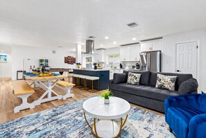 A modern living space with a dining area, kitchen, and seating area.