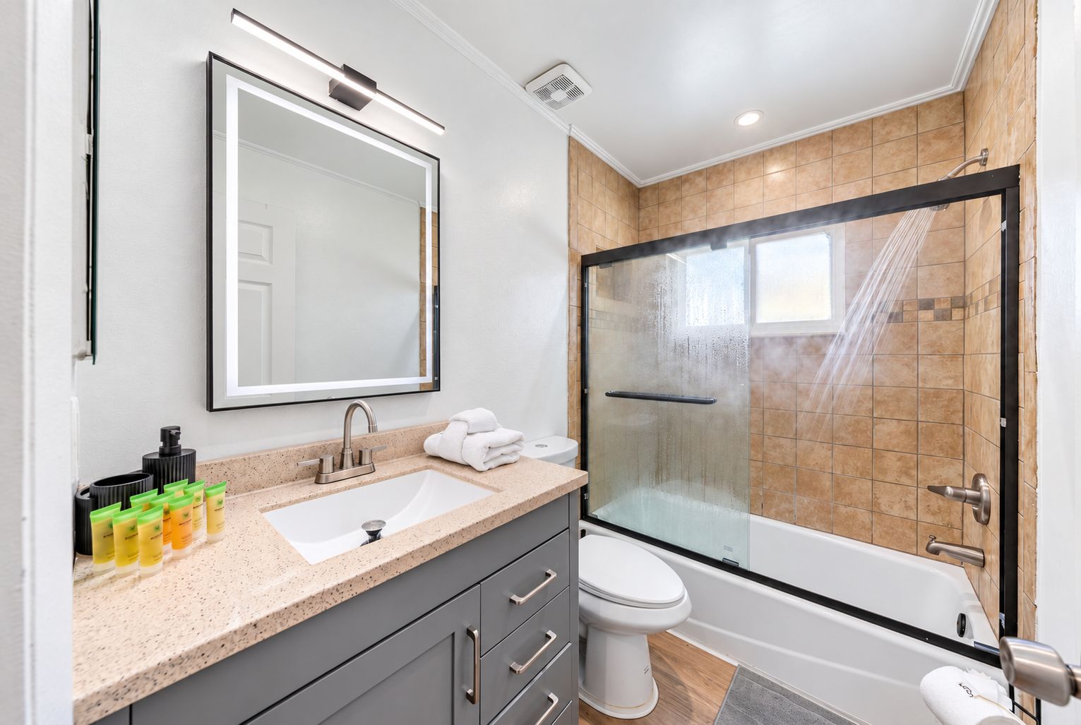 Une salle de bain moderne avec une douche à parois de verre, un grand miroir et un lavabo agrémenté d’articles de toilette.
