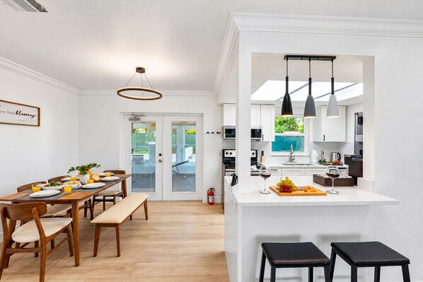 A modern kitchen with white cabinets, a central island, and pendant lighting.