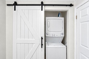 Un cuarto de lavado con una puerta blanca, una lavadora y un planchador.