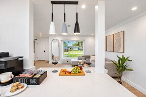 Una sala de estar moderna con una barra de café, una mesa de comedor con comida y vistas al exterior.