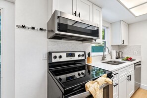 Een moderne keuken met roestvrijstalen apparatuur, witte kasten en een raam dat voor natuurlijk licht zorgt.