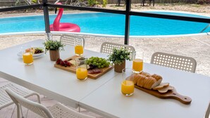 A dining table set with food and drinks, overlooking a swimming pool. - Lounge & Play in Chic North Tampa Home (Tampa)