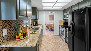 Eine moderne Küche mit Granit-Arbeitsplatten, einem schwarzen Kühlschrank und einem Essbereich mit Holztisch und Stühlen.
