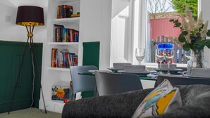 Een eethoek met een tafel voor twee personen, een boekenkast en een lamp.