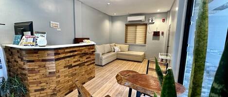 A modern reception area with a wooden reception desk, a sofa, and a dining table.