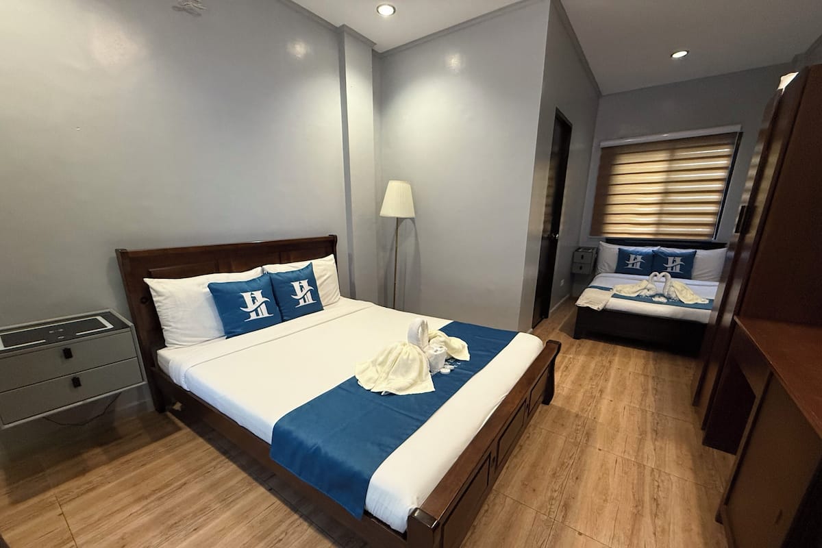 A hotel room with a large bed, a smaller bed, a desk, and a wardrobe.