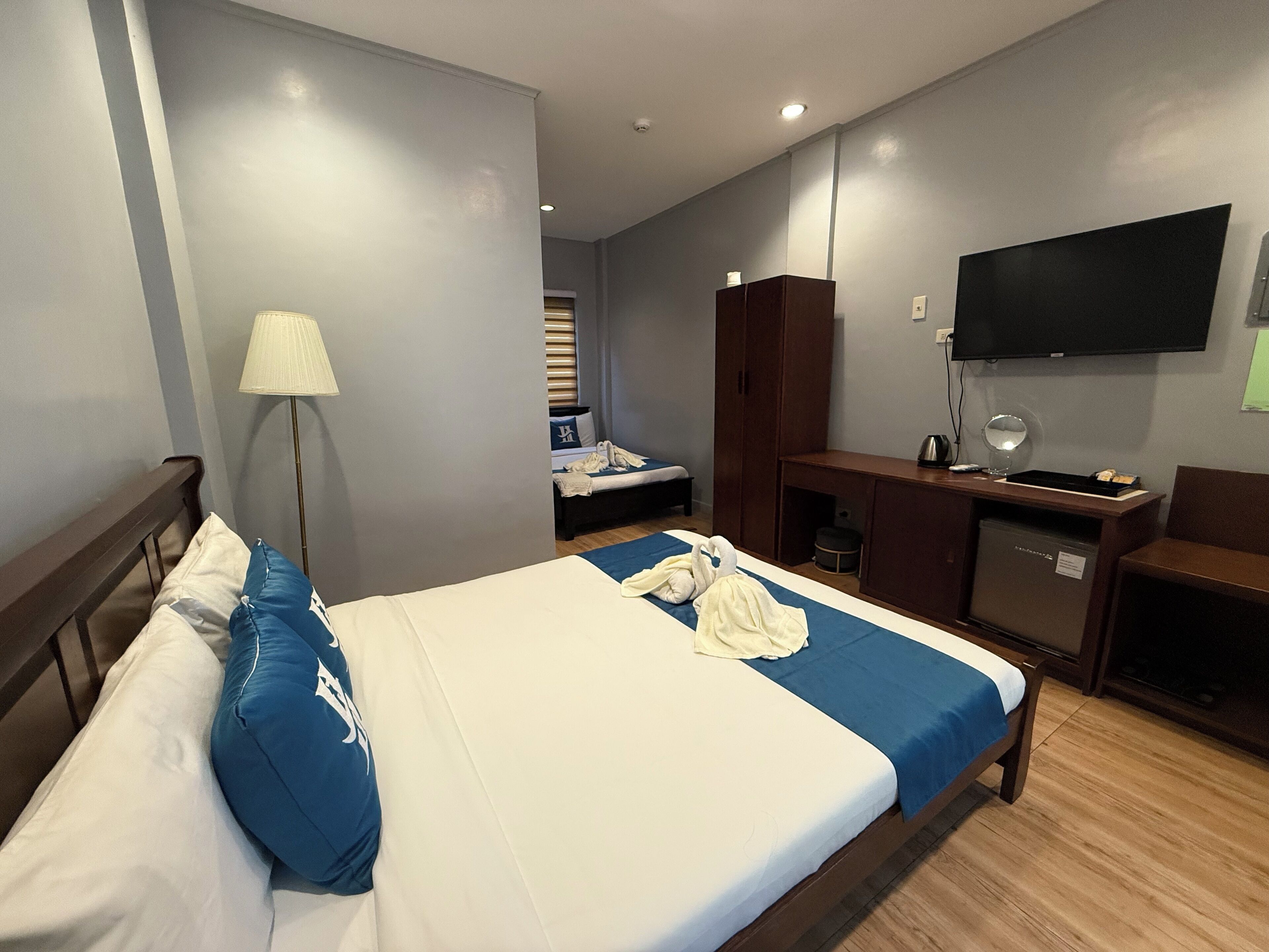 A hotel room with a bed, a desk, a wardrobe, and a TV.
