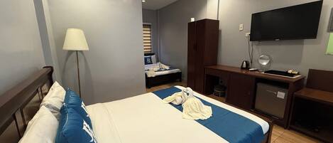 A hotel room with a bed, a desk, a wardrobe, and a TV.