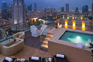 Terraza en la azotea con piscina, sillas de descanso y vista panorámica de la ciudad.