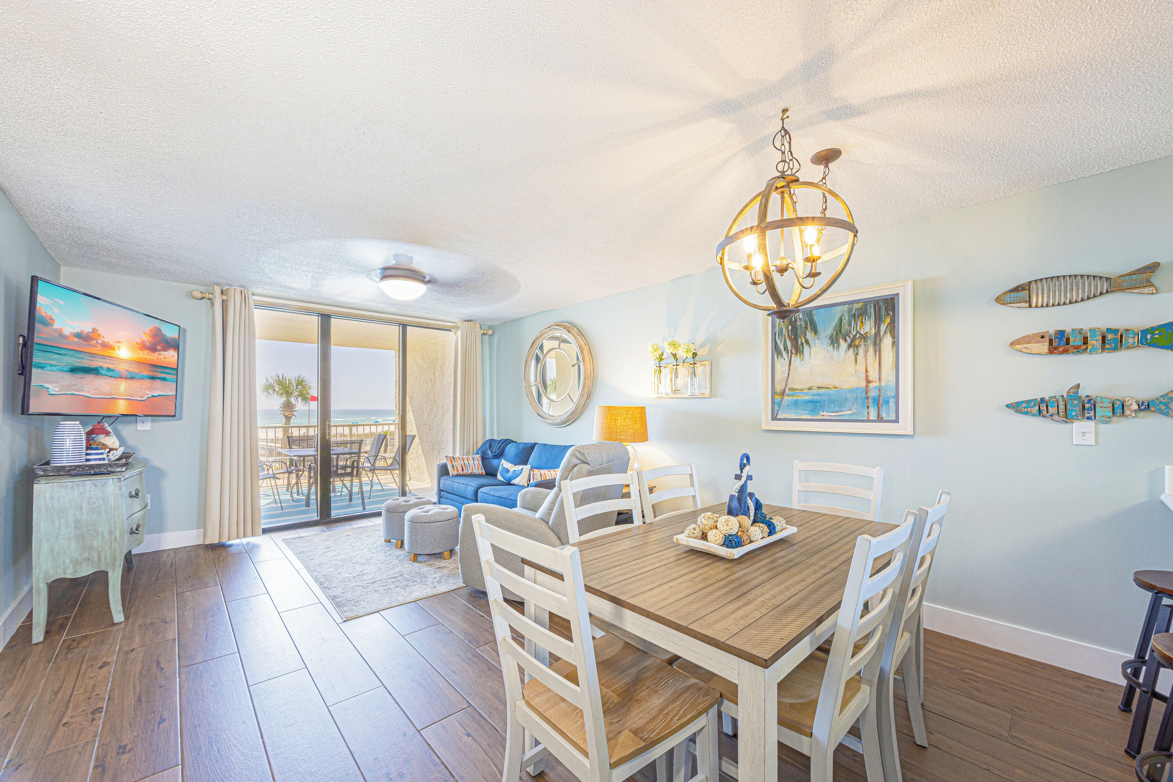 A dining area with a wooden table and chairs, a chandelier, and artwork on the walls.