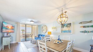 Een eethoek met een houten tafel en stoelen, een kroonluchter en kunstwerken aan de muur.