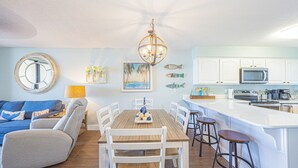 Een moderne keuken met witte kasten, een houten eettafel en barstoelen.