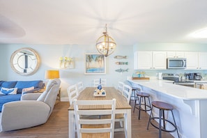 A modern kitchen with white cabinets, a wooden dining table, and bar stools. - Seaside Beach & Racquet #3203 (Orange Beach)