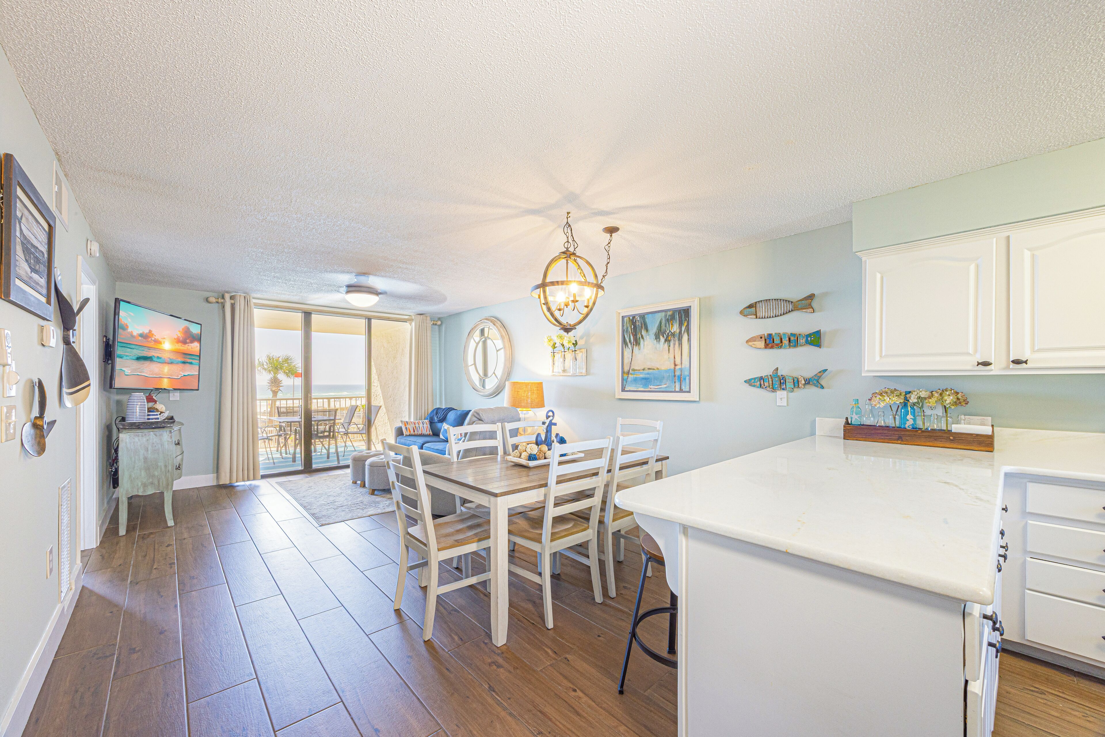 A spacious kitchen with a dining area, wooden flooring, and a view to the outside.