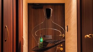 A hallway with wooden doors, a mannequin with a bottle, and a black shelf. - LLOYD's HAKATA (Fukuoka)