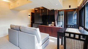 A modern living room with a sofa, a dining table, and a kitchen area. - LLOYD's HAKATA (Fukuoka)