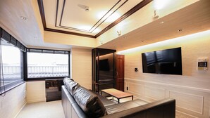 A modern interior with a sofa, a small table, a flat-screen TV, and a window with a view. - LLOYD's HAKATA (Fukuoka)