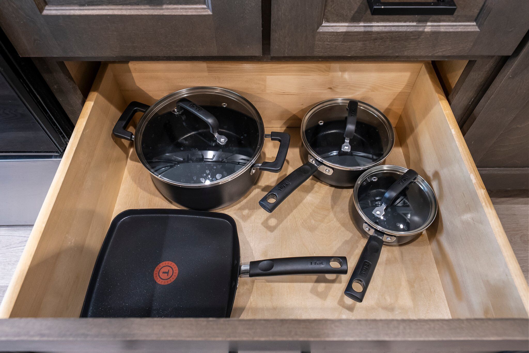 A kitchen drawer with three pots and a pan.