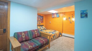 Ein Zimmer mit einer Couch, einem Bett und einer Wand mit Kunstwerken.