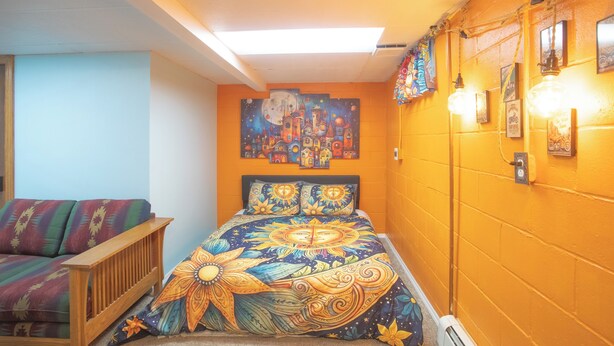 Ein Zimmer mit einem Bett, einer Couch und einer Wand mit Kunstwerken und Leuchten.