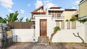 A modern two-story house with a wooden door, stone steps, and a white wall with geometric patterns. - Samvara Villa by Kozystay - Ubud (Ubud)