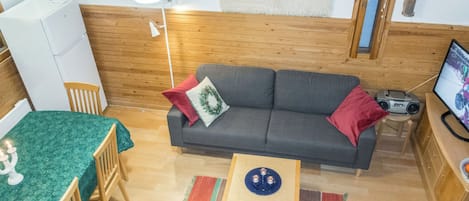 A cozy living room with a sofa, a television, and a small table.
