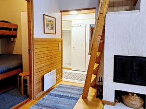 A room with a bunk bed, a radiator, a wooden wall, a framed picture, and a staircase.