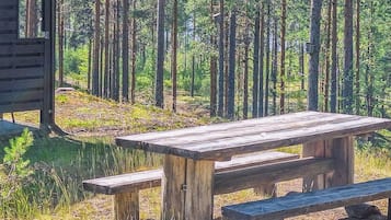 Puinen piknikpöytä penkkeineen metsäisellä alueella.
