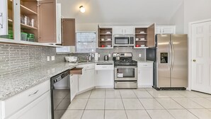 Una cocina moderna con armarios blancos, electrodomésticos de acero inoxidable y salpicadero de azulejos.