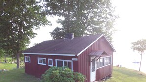 A small, single-story house with a red exterior and white trim, a chimney, and a small porch.